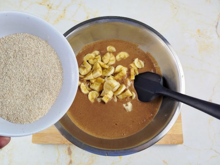 Massa acomodada em uma tigela com banana, aveia, fermento em pó e água adicionados.