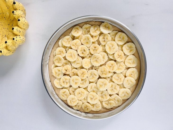 Uma forma untada com a massa e uma camada de bananas.