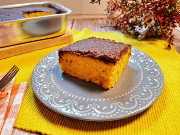 Fatia de bolo de cenoura com cobertura de chocolate no prato.