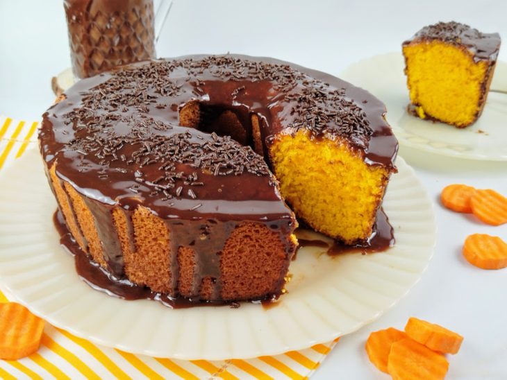 Bolo de cenoura com cobertura de chocolate desenformado e decorado com granulados.