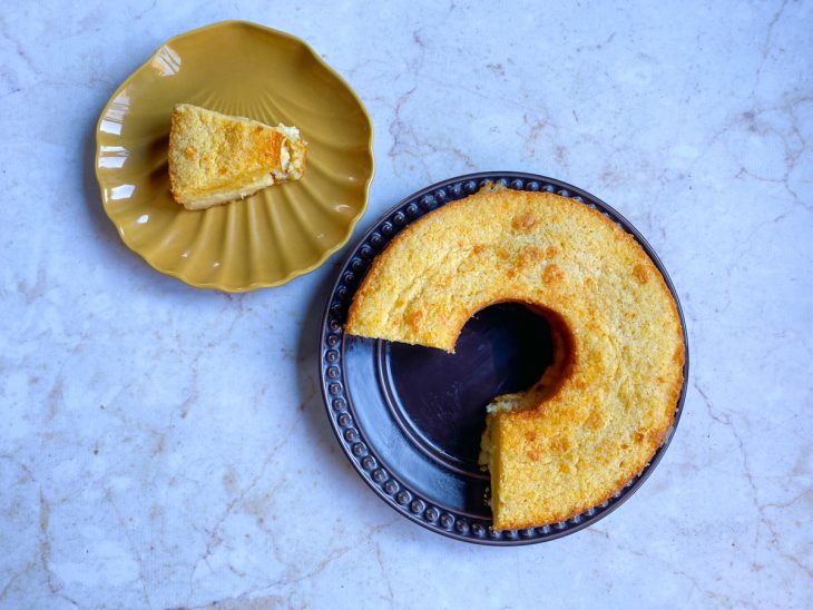 travessa com o bolo de flocão com queijo e uma fatia do bolo em um pires