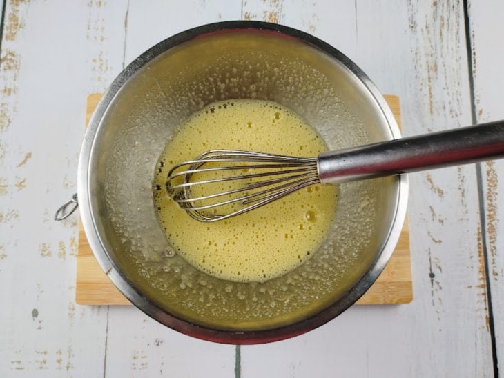 Uma tigela com fouet e a mistura de ovos e açúcar.