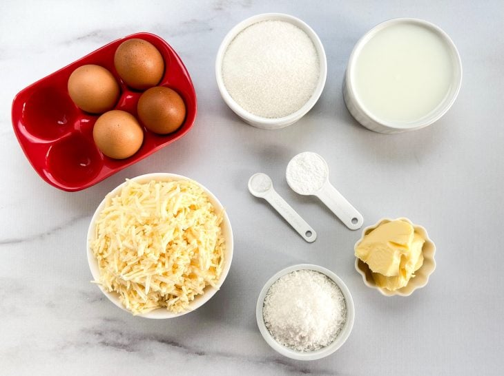 Ingredientes para preparar o bolo de mandioca ralada em uma mesa.