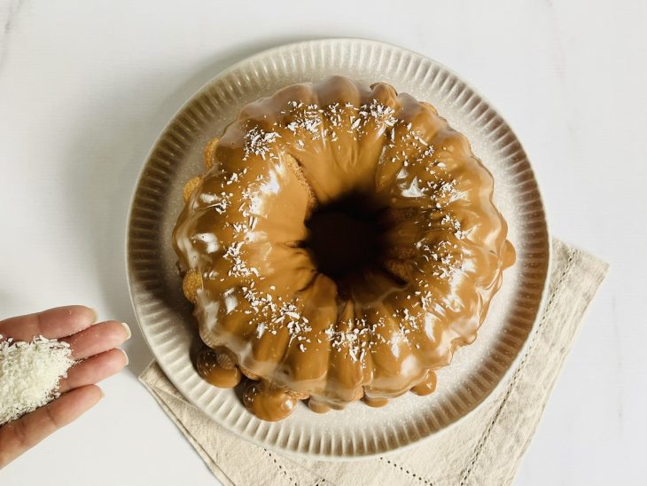 Bolo coberto por doce de leite misturado com creme de leite, e decorado com coco ralado.