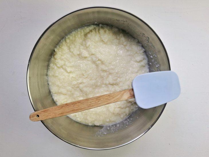 Leite de coco, leite condensado e coco ralado incorporados a tapioca granulada com leite na tigela.