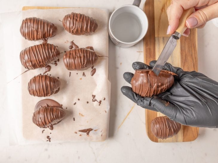 Bombons com bordas sendo aparadas com uma faca.