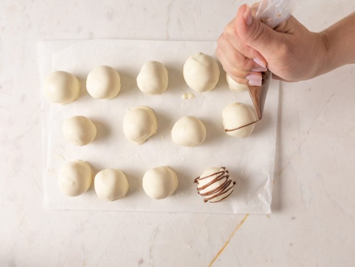 Bombons sendo decorados com chocolate ao leite.