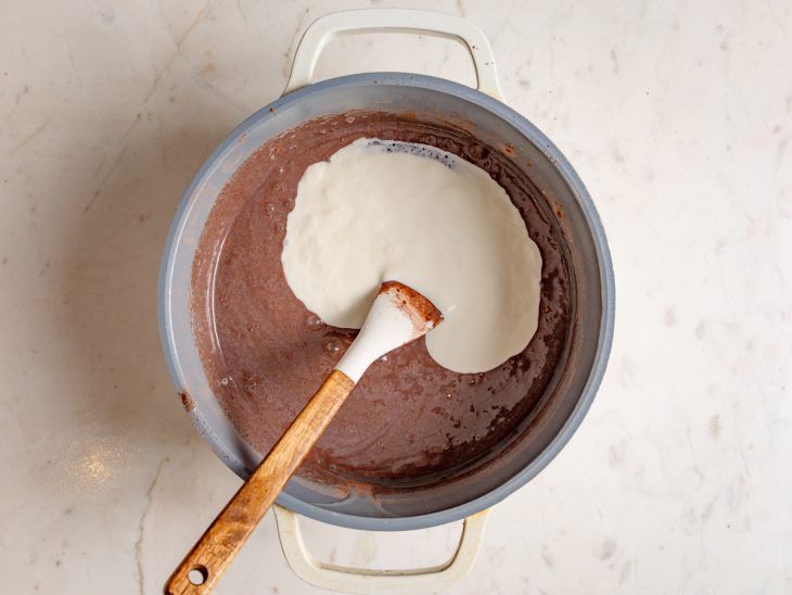 Leite condensado, chocolate em pó e creme de leite em uma panela.