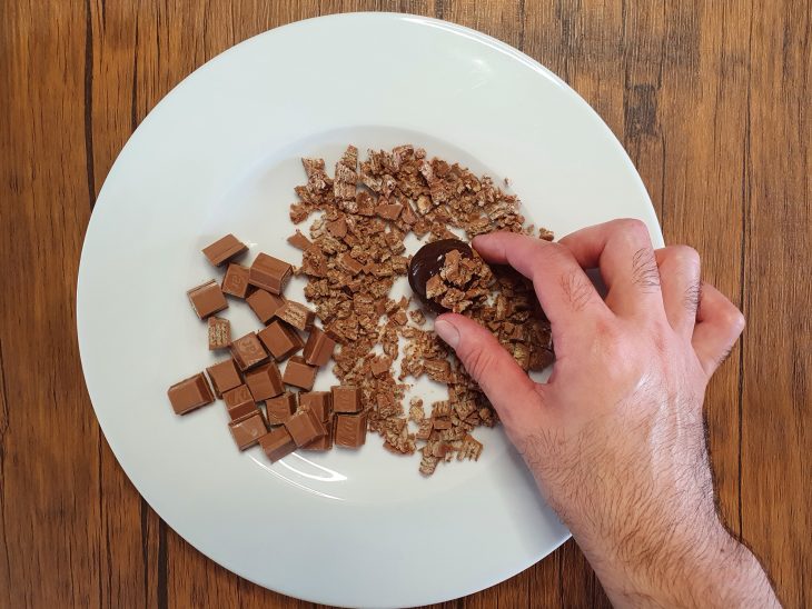 o brigadeiro é passado na farofinha de kit Kat