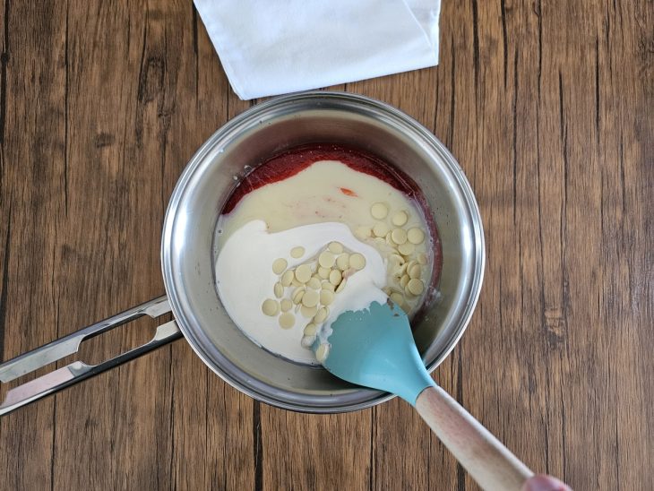 Uma panela com a mistura da calda de morango, leite condensado, creme de leite e chocolate branco.