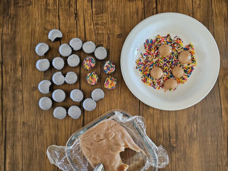 Um prato com chocolate granulado colorido e forminhas com o brigadeiro.