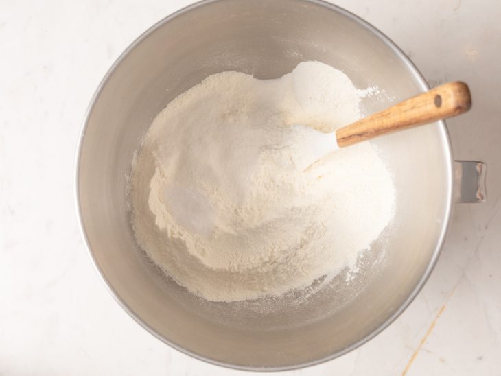 Uma tigela com farinha, fermento, açúcar, água e sal.