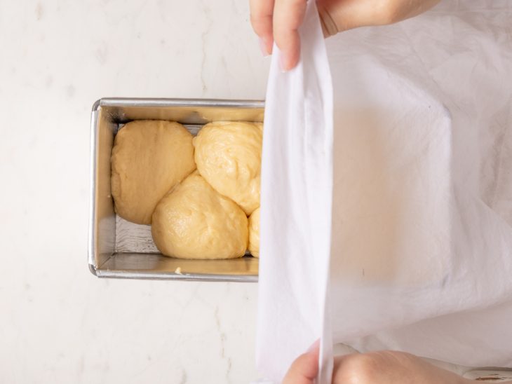 Assadeira com brioche sendo coberta com pano.