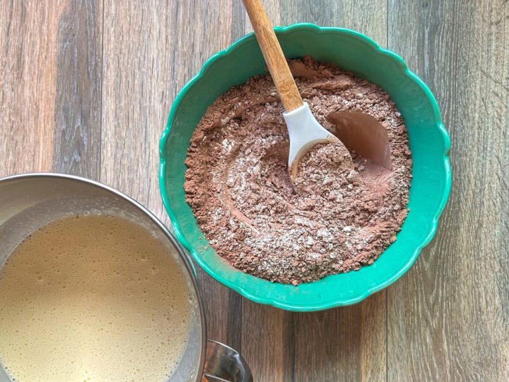 Tigela com farinha e chocolate em pó ao lado do recipiente com ovos, açúcar e óleo.