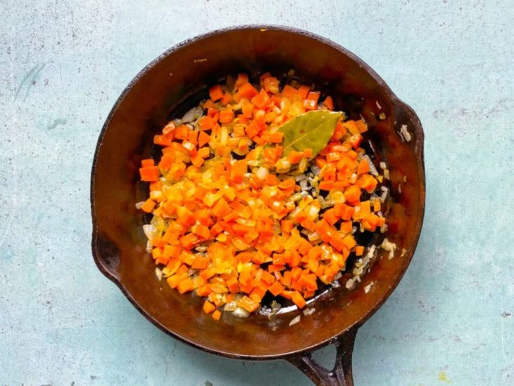 Panela de ferro com temperos e legumes refogados.