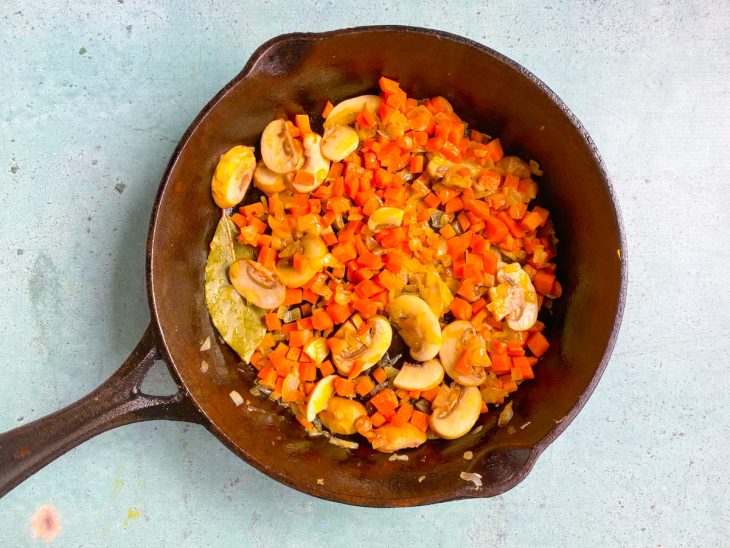 Panela de ferro com legumes e temperos refogados.