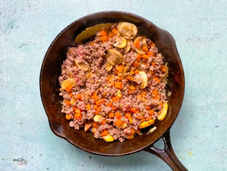 Frigideira de ferro com carne moída com legumes e temperos.