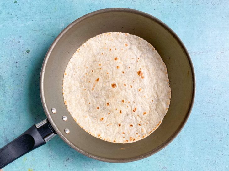 Frigideira com tortilha com alguns pontos tostados.