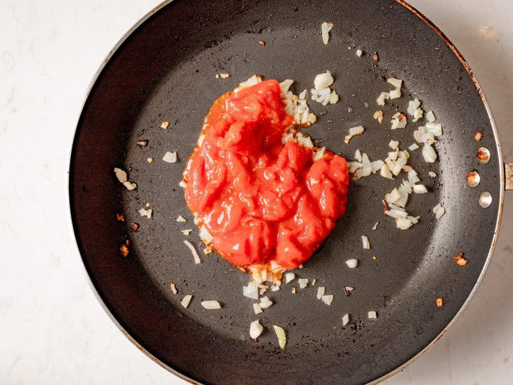 Frigideira com cebola picada e molho de tomate.