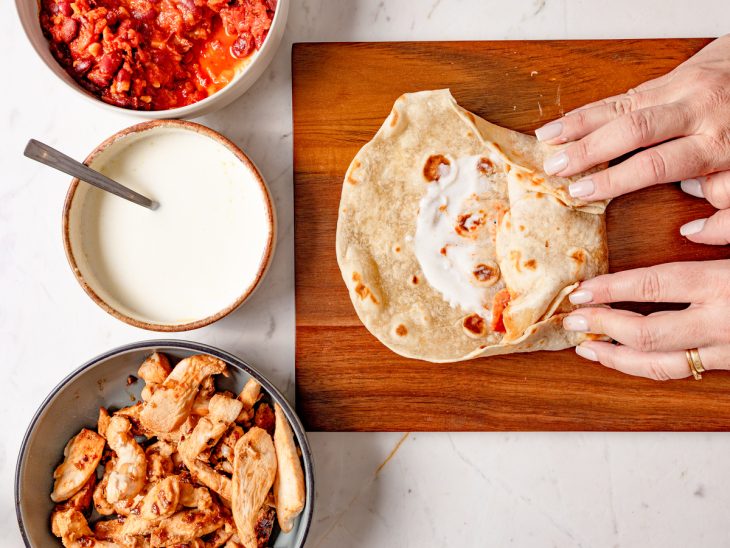 Bordas da tortilha sendo dobradas para fechar o burrito.