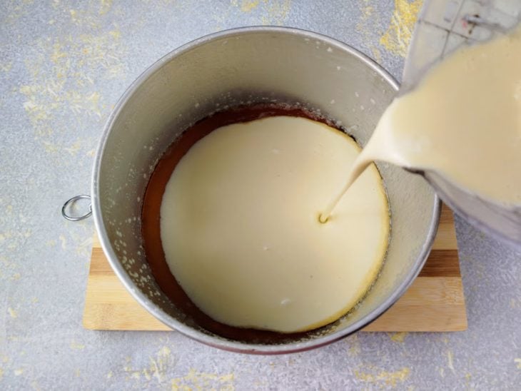 Uma forma com desmoldante, caramelo e a massa do bolo sendo despejada.