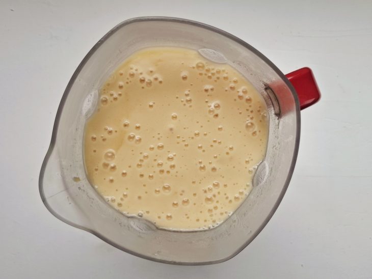 Mandioca batida com água e tablet de caldo de galinha em um liquidificador.