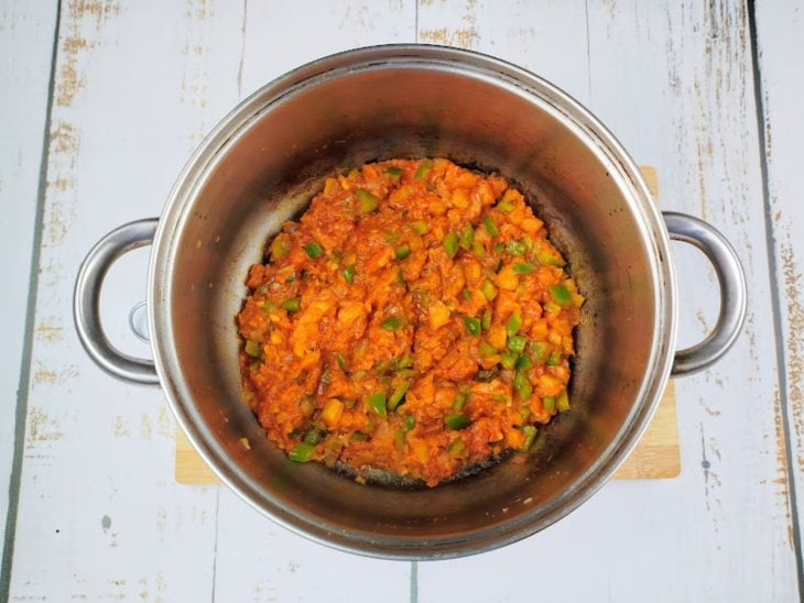 Uma panela com pimentão, tomate, cebola, alho e temperos cozinhando.