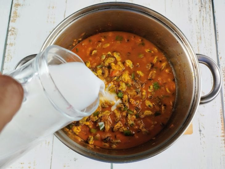 Leite de coco sendo adicionado à panela com a mistura do caldo de sururu.