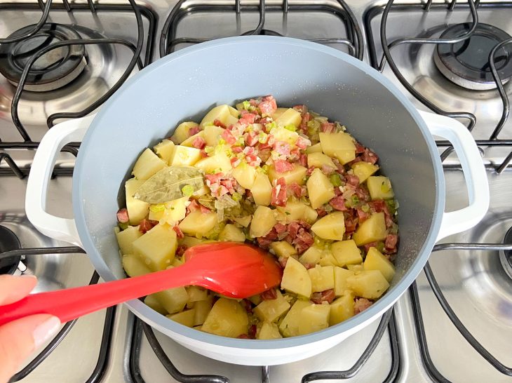 Uma panela com a linguiça temperada e a batata ao fogo.