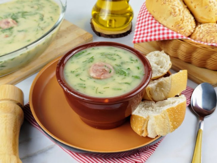 Caldo verde pronto para servir, acompanhado por pães.