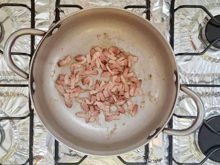 Bacon fritando em uma panela com banha derretida.