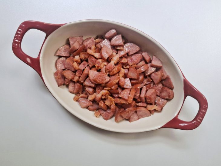 Bacon e calabresa fritos e reservados em um recipiente.