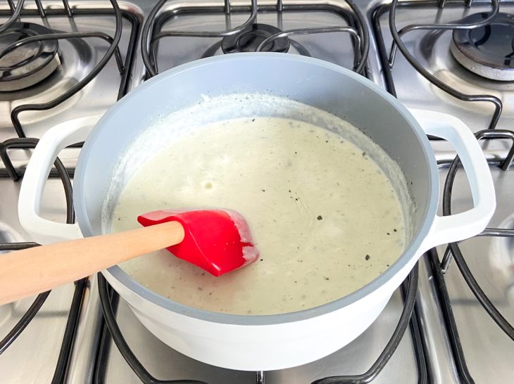 Uma espátula em panela com a mistura de manteiga, farinha, leite, sal e gorgonzola.