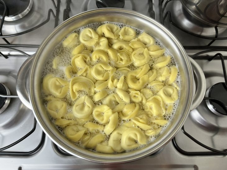 Uma panela com água cozinhando capelettis.