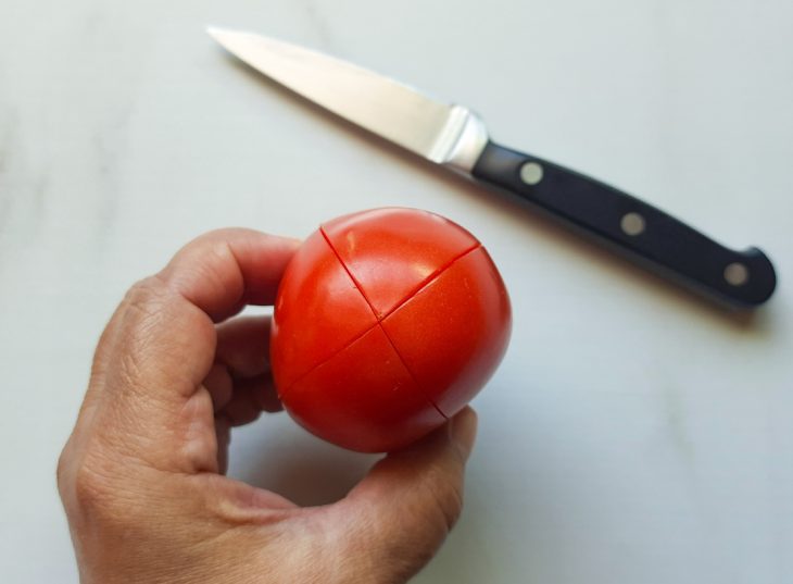 Um tomate com cortes na superfície.