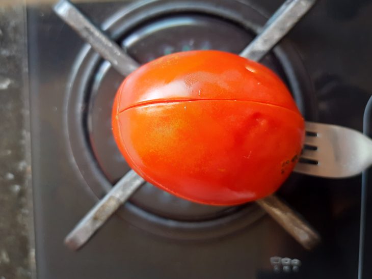 Um tomate sobre a chama do fogo.