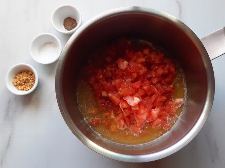 Uma panela com tomates picados, manteiga, azeite e temperos.