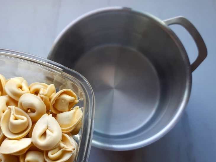 Uma panela com água e a adição do capeletti.