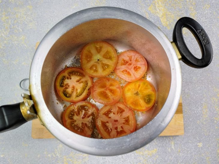 Camada de rodela de tomates no fundo da panela de pressão.