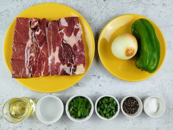 Ingredientes necessários para preparar a carne-seca desfiada em uma bancada.