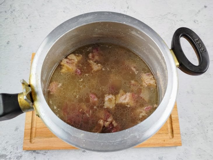 Cubos de carne em uma panela de pressão com água.