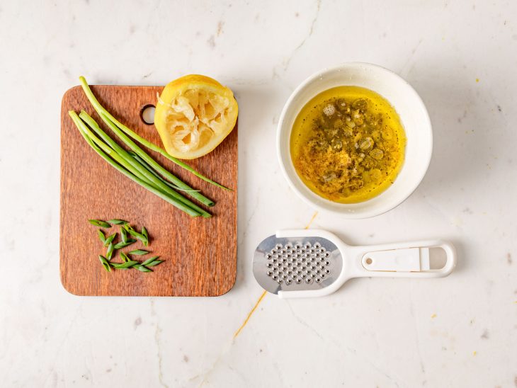 tábua com cebolinha cortada e limão-siciliano para fazer um molho.