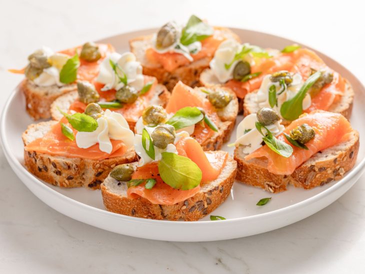 carpaccio de salmão defumado servido em pedaços de pão baguete.