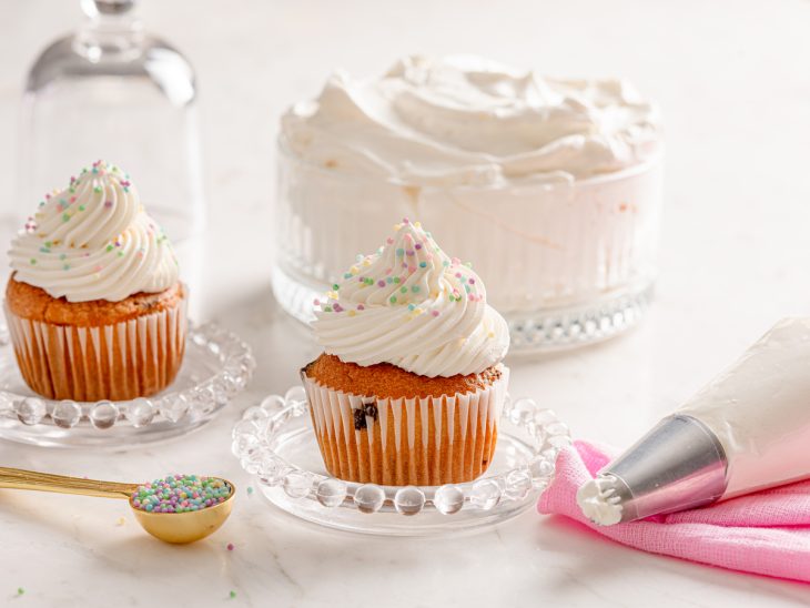 Recipiente e cupcakes com chantilly de chocolate branco.