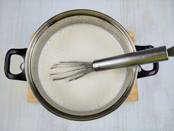 Uma panela com a mistura de açúcar, amido e leite.