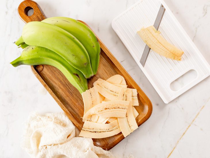 Uma tábua com as bananas fatiadas em tiras.