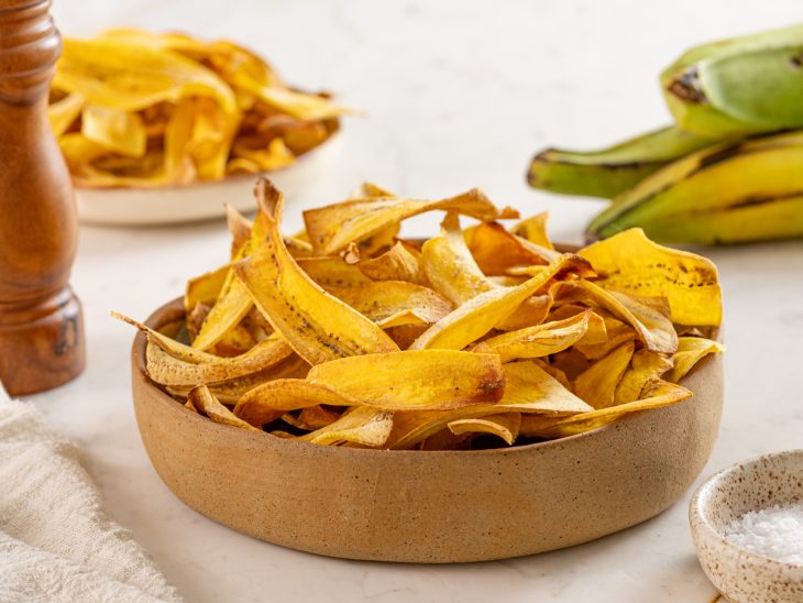 Um recipiente com chips de banana de forno.