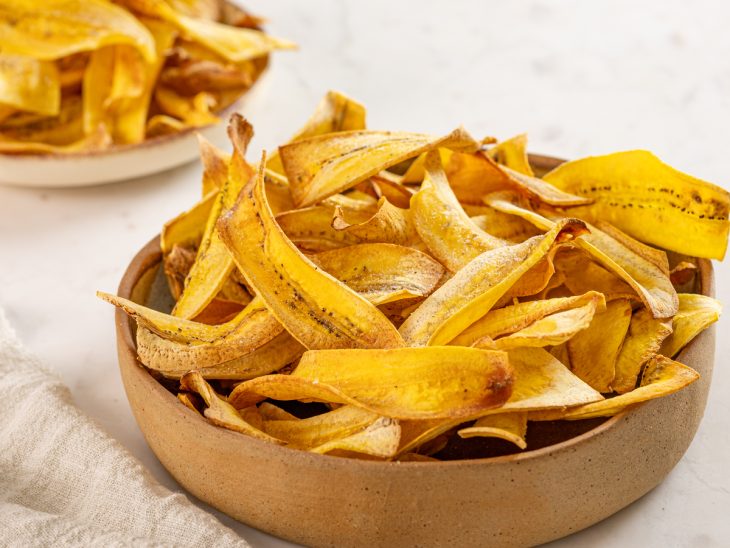 Um recipiente com chips de banana de forno.