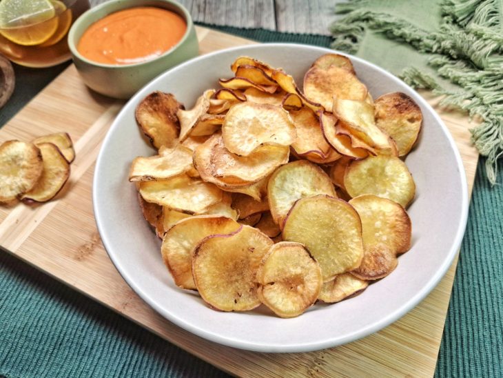 Chips de batata-doce servidos em uma recipiente redondo e fundo.