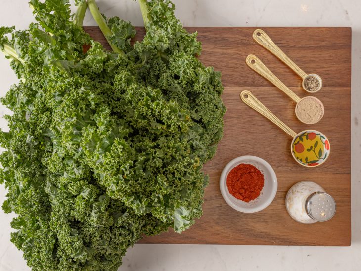 Ingredientes do chips de couve kale reunidos na bancada em cima da tábua.